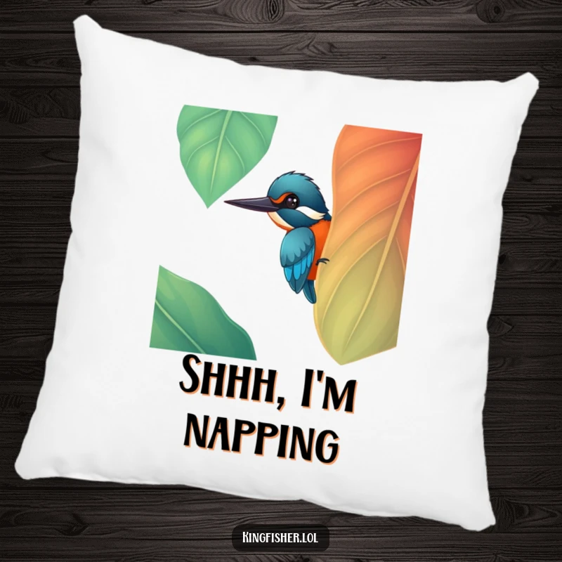Funny cheerful kingfisher bird peeking from behind a big, colorful leaf on a soft pillow, a perfect funny gift.