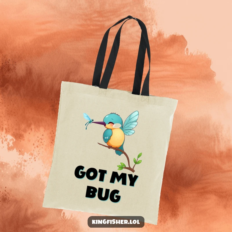 Funny Kingfisher Tote Bag: A smiling kingfisher bird playfully pecks at a shimmering dragonfly, perfect for carrying treasures.