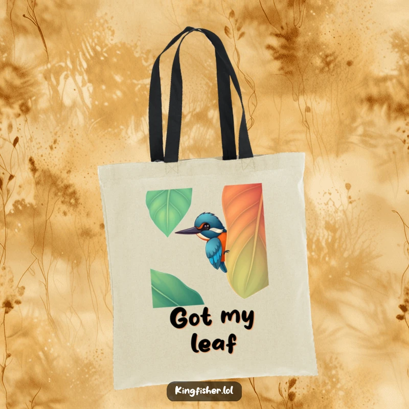 Funny cheerful kingfisher bird peeking from a large, colorful leaf on a durable tote bag, a practical funny gift.